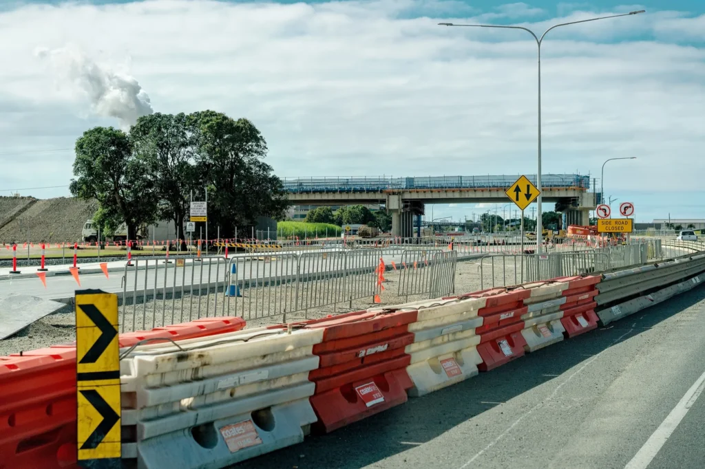 Water-filled barriers and temporary fencing separating a roadworks zone near a highway overpass