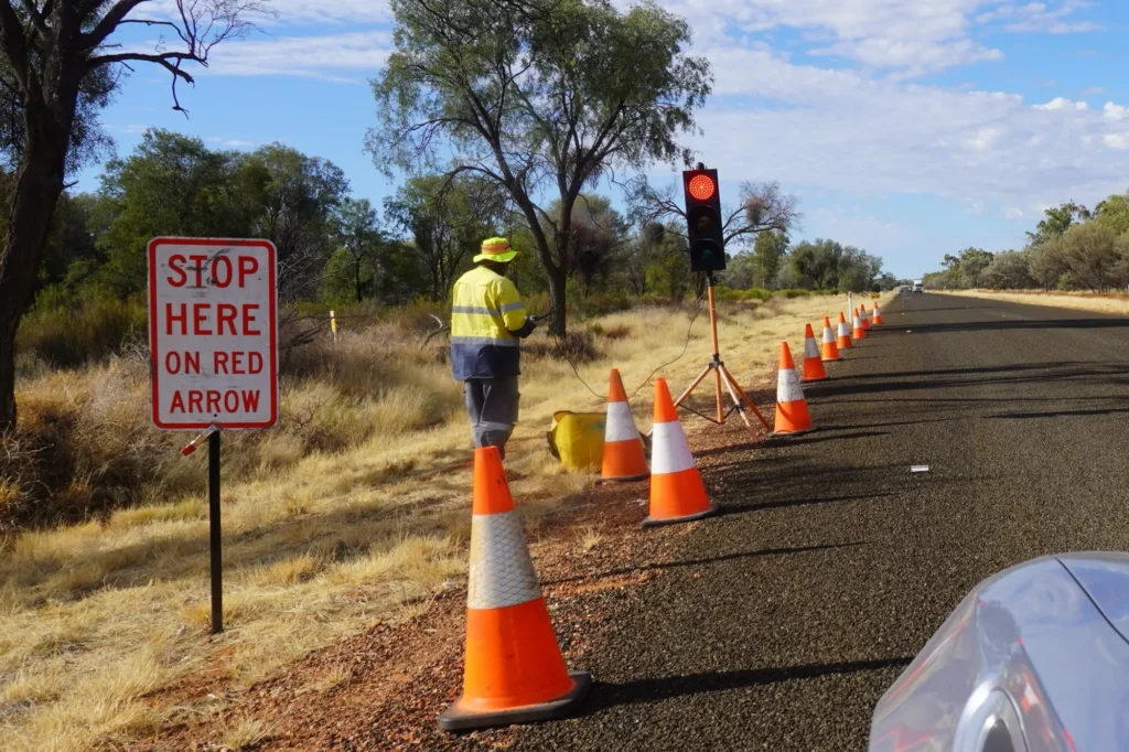 Portable "Stop here on red arrow" traffic signal and cones on a rural outback road