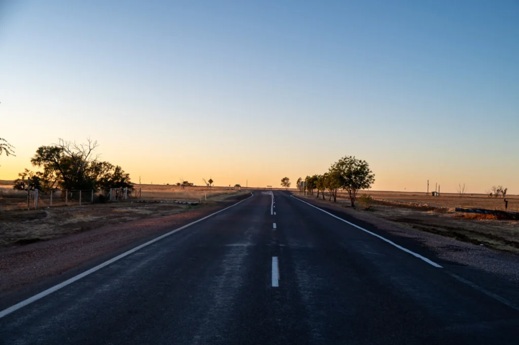 Open regional highway stretching to the horizon at dusk across flat plains